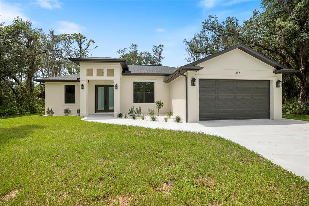 A single-story house with a white stucco exterior, dark roof, and a two-car garage — 317 DORMAN STREET, PORT CHARLOTTE, FL