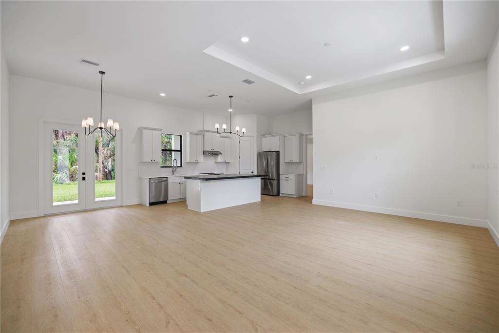 An open-concept kitchen and living area features white cabinetry, a center island, and light wood flooring — 317 DORMAN STREET, PORT CHARLOTTE, FL
