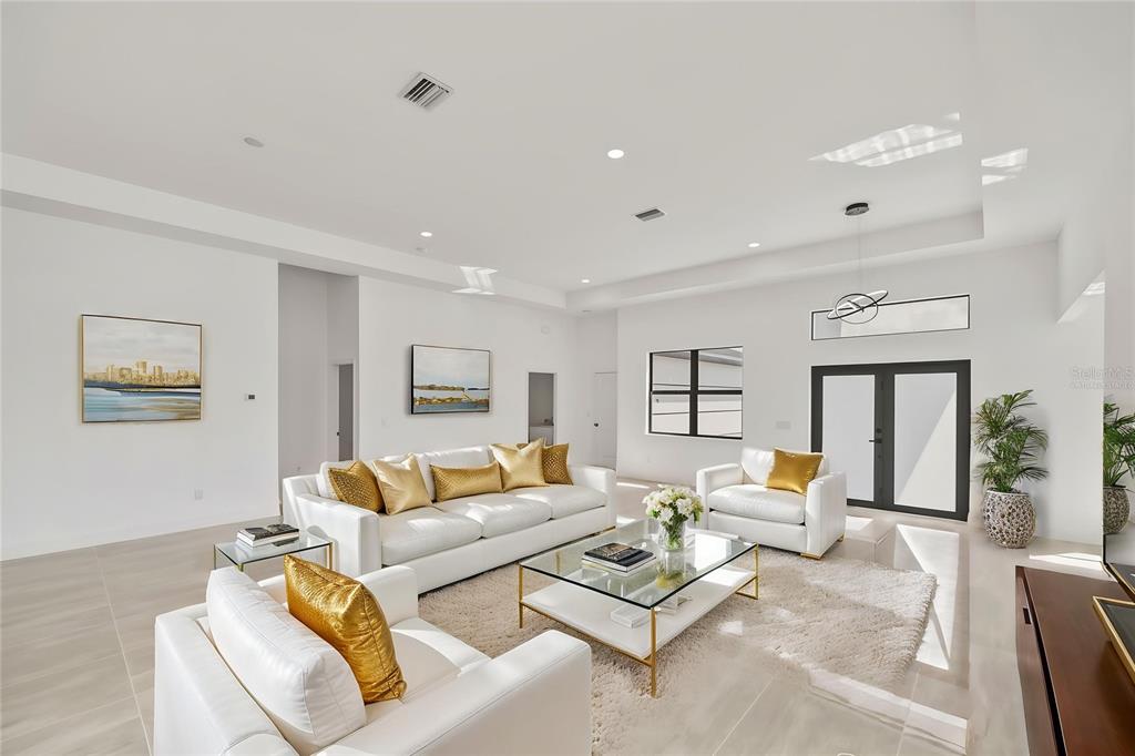 A bright, modern living room features white sofas, gold accents, and a glass coffee table — 10165 & 10157 KINGSVILLE DRIVE, PORT CHARLOTTE, FL