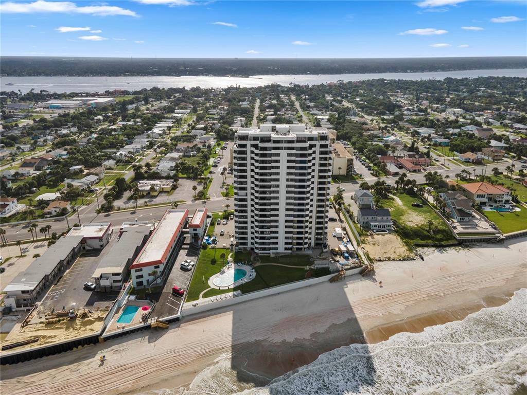 An aerial view shows a tall residential tower on a beach with two swimming pools — 1420 N ATLANTIC AVENUE UNIT 703, DAYTONA BEACH, FL