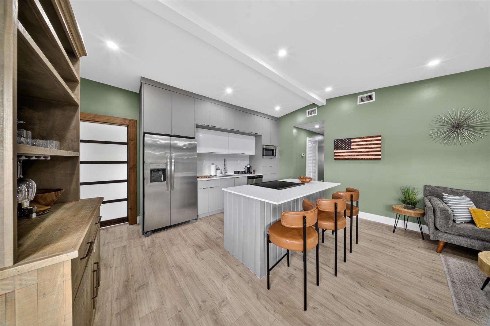 A modern kitchen features gray cabinetry, a central island with bar seating, and green walls — 801 SE 15th Street, Stuart FL 34994, STUART, FL