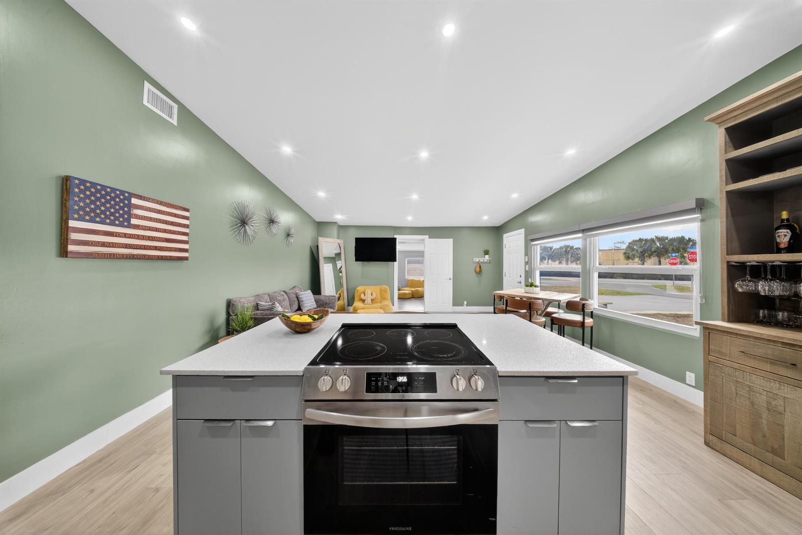 A kitchen island with a built-in stove sits in a room with sage green walls — 801 SE 15th Street, Stuart FL 34994, STUART, FL