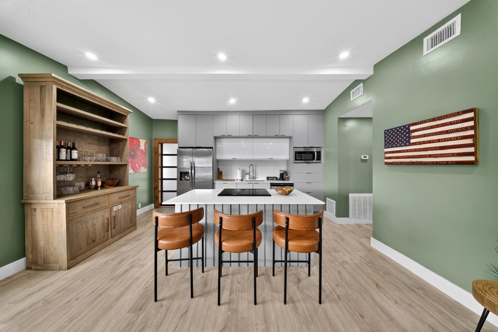 A modern kitchen features a central island with three bar stools, grey cabinetry, and green walls — 801 SE 15th Street, Stuart FL 34994, STUART, FL