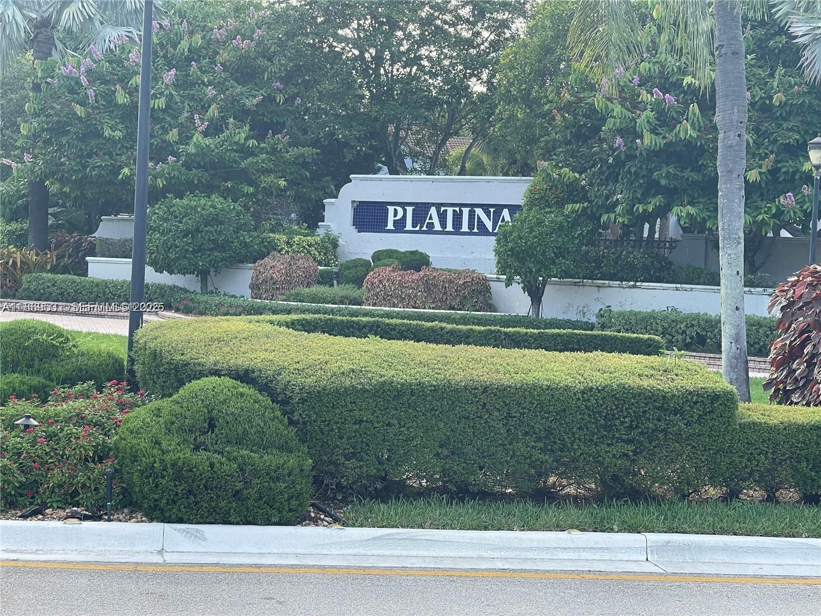 A white sign with the word Platina sits behind manicured hedges and lush landscaping — 5133 Brisata # L, Boynton Beach FL 33437, BOYNTON BEACH, FL