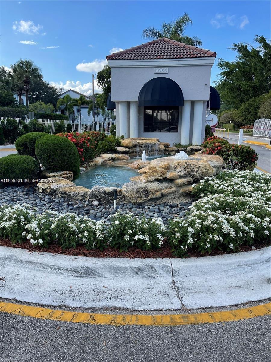 A stone fountain with water features sits in front of a gated community entrance building — 5133 Brisata # L, Boynton Beach FL 33437, BOYNTON BEACH, FL