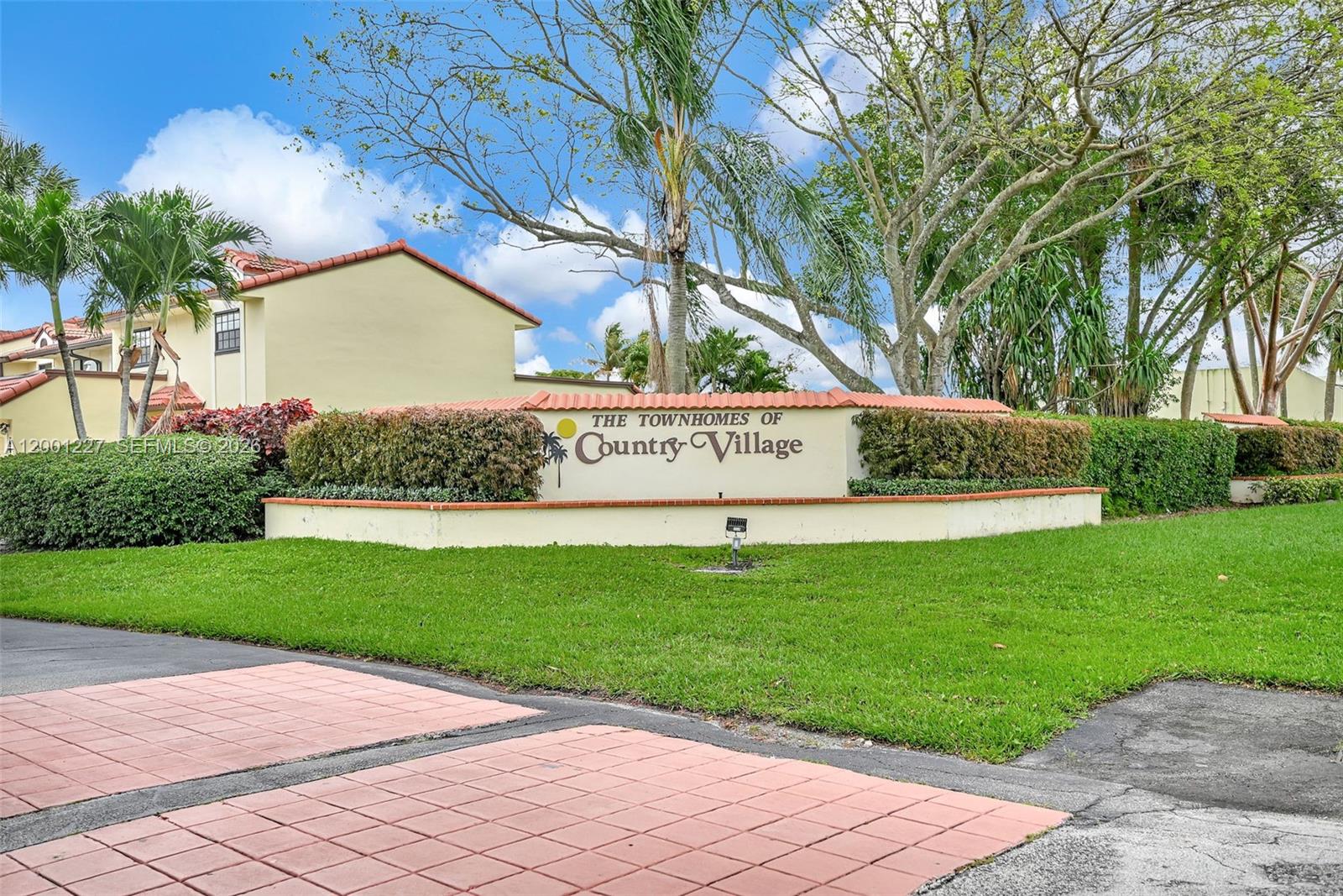 A sign for The Townhomes of Country Village stands in front of a residential building — 19252 NW 65th Ct, Hialeah FL 33015, HIALEAH, FL