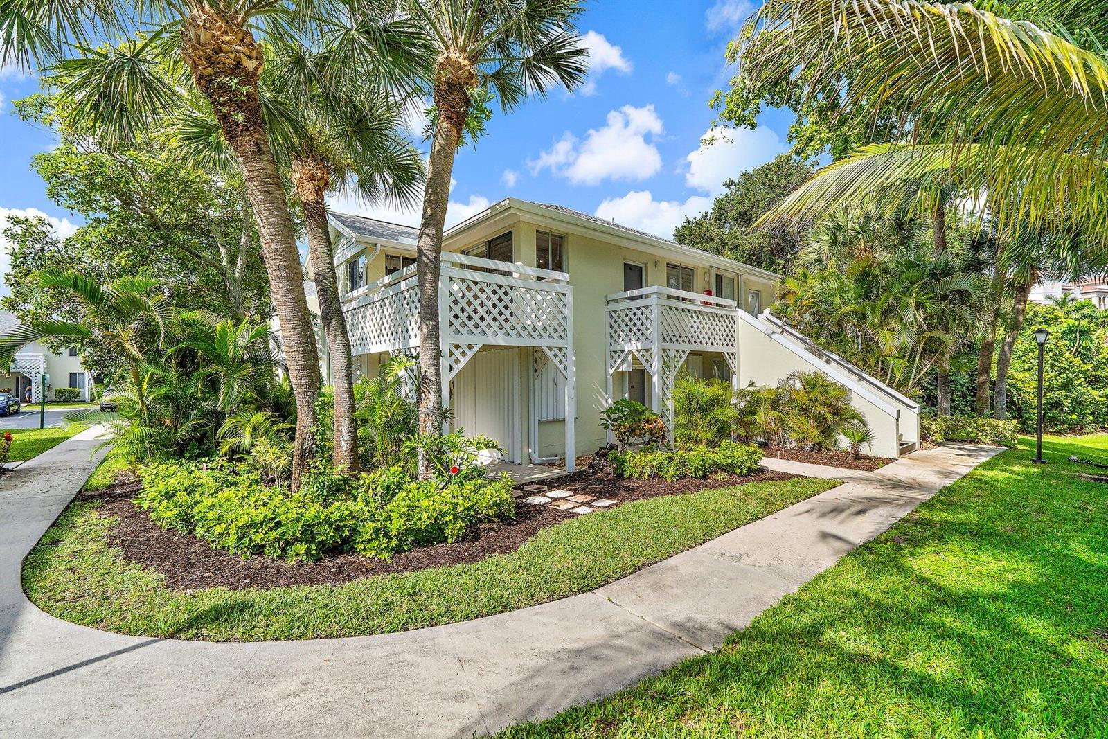 A two-story light-colored building with white lattice balconies surrounded by palm trees and landscaping — 353 S Us Hwy 1 # B8, Jupiter FL 33477, JUPITER, FL