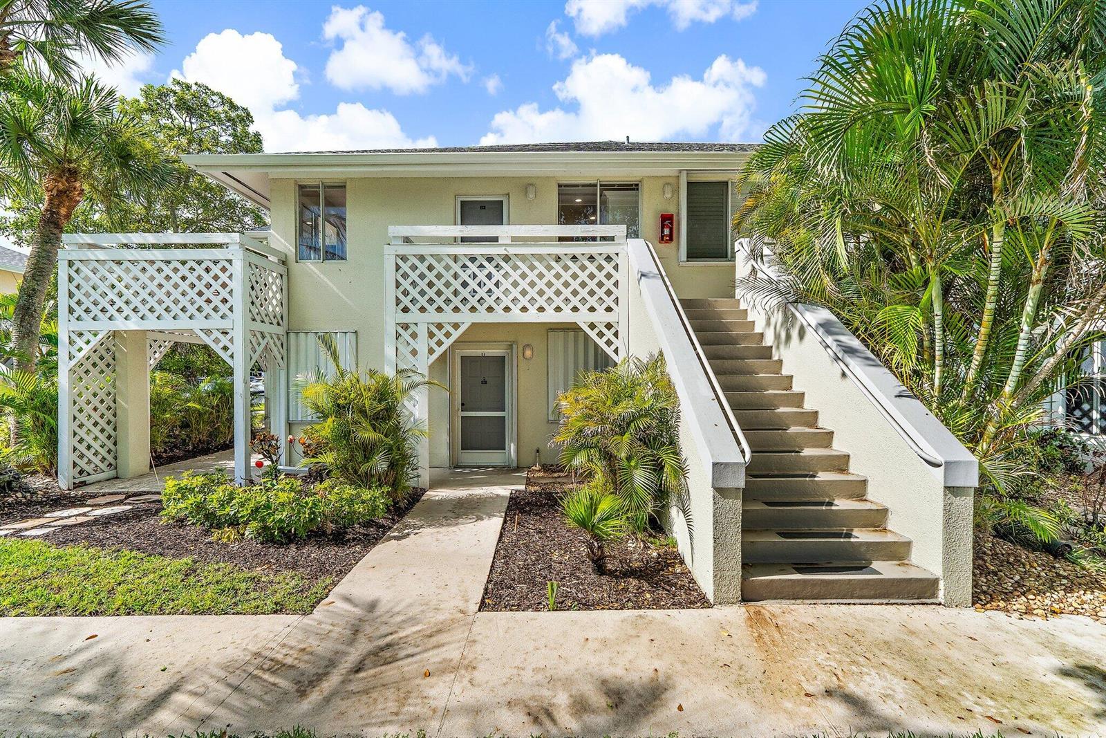 A two-story apartment building exterior features a concrete staircase leading to an upper-level balcony — 353 S Us Hwy 1 # B8, Jupiter FL 33477, JUPITER, FL