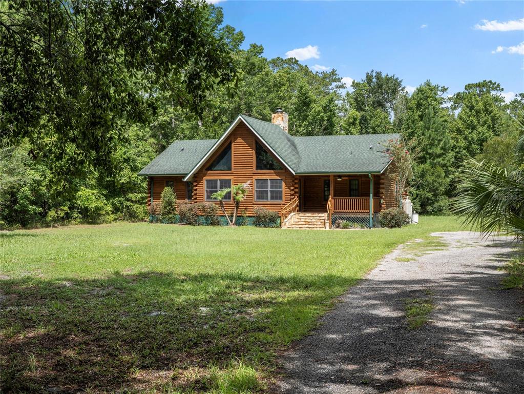 A log cabin home with a green roof sits on a grassy lot with trees — 712 MALLARD DRIVE, SANFORD, FL