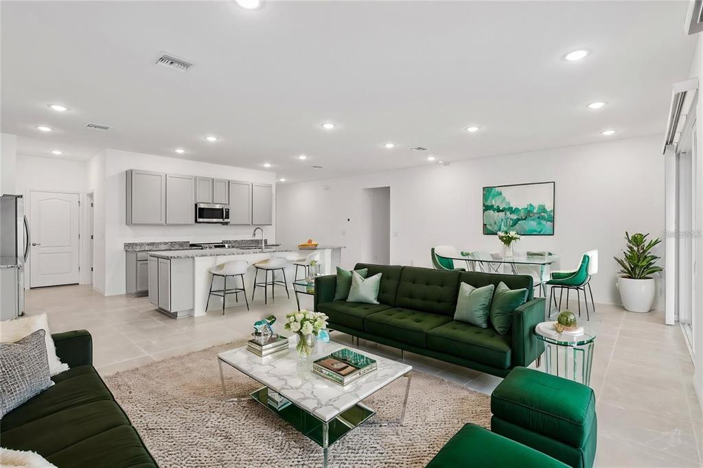 An open-concept living and dining area features a green sofa, marble coffee table, and kitchen — 2275 NW 248TH WAY, NEWBERRY, FL