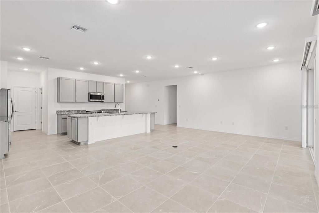 A bright, open-concept kitchen and living area featuring light gray cabinets and tiled flooring — 2275 NW 248TH WAY, NEWBERRY, FL