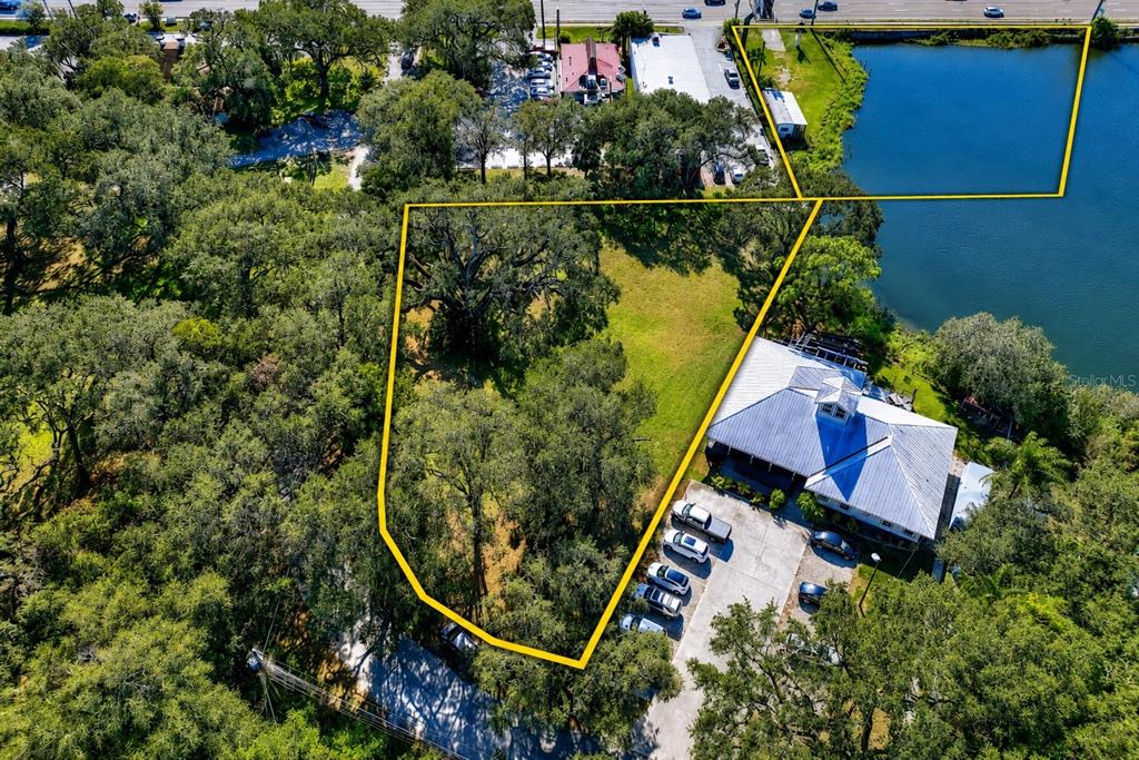 An aerial view shows a vacant lot outlined in yellow next to a building — 1214 W BRANDON BOULEVARD, BRANDON, FL