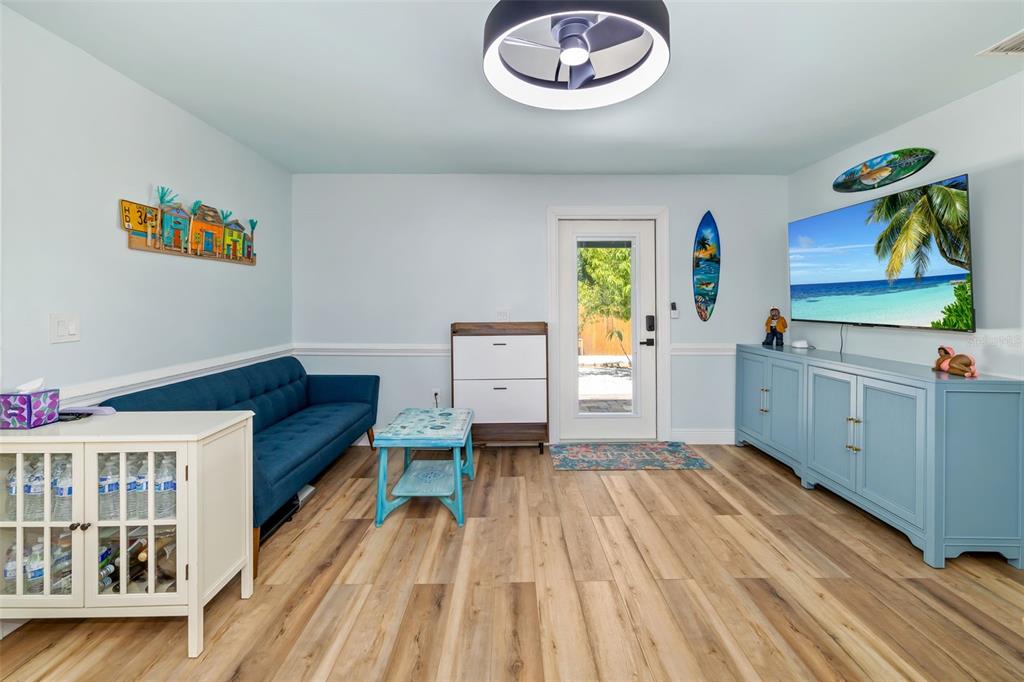 A living room features a blue sofa, light wood flooring, a television, and a ceiling fan — 2549 19TH STREET, SARASOTA, FL