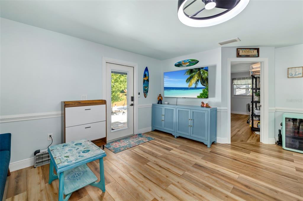 A living room features light blue walls, wood-look flooring, a television, and a glass door — 2549 19TH STREET, SARASOTA, FL