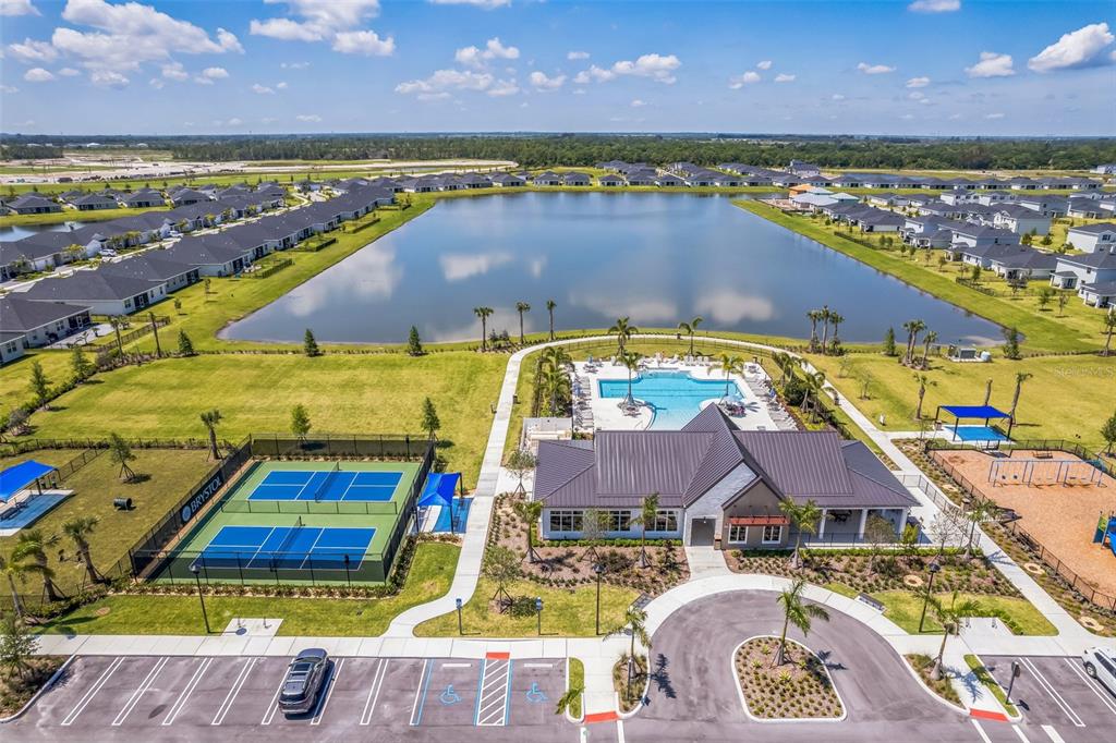 An aerial view shows a community clubhouse with a pool, tennis courts, and a lake — 5428 NW CAMBERLY COURT, PORT ST LUCIE, FL