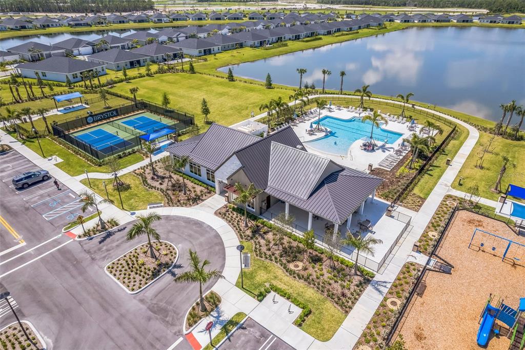 An aerial view shows a community clubhouse with a pool, tennis courts, and a playground — 5428 NW CAMBERLY COURT, PORT ST LUCIE, FL