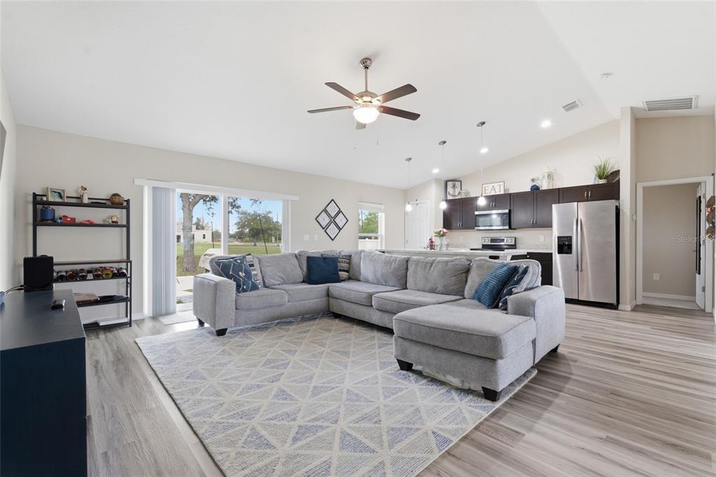 A living room with a gray sectional sofa, area rug, and an open-concept kitchen — 13880 SW 45TH TERRACE, OCALA, FL