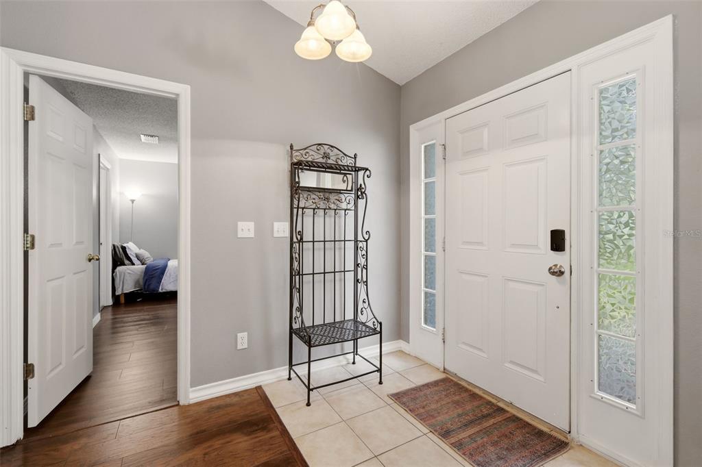 An entryway features a white front door, tile flooring, and a black metal hall tree — 1313 OAK VALLEY BOULEVARD, MINNEOLA, FL