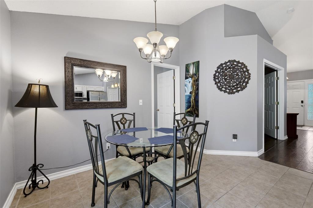 A dining area features a glass table, four chairs, a chandelier, and a wall mirror — 1313 OAK VALLEY BOULEVARD, MINNEOLA, FL