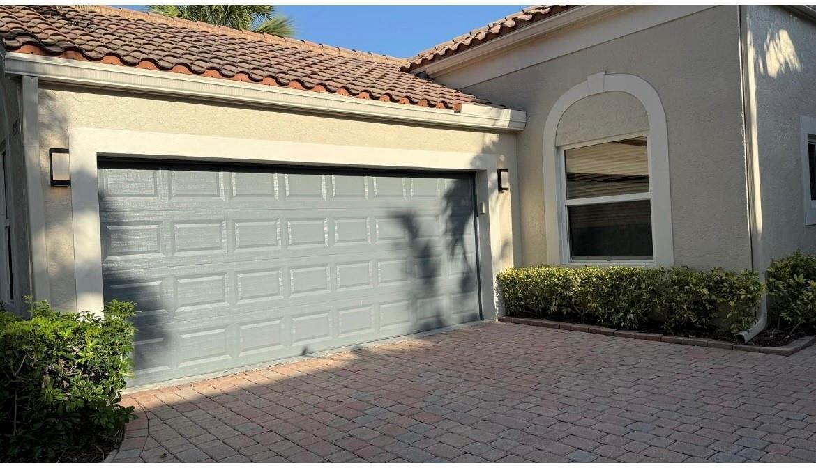 A gray garage door with a tiled roof and a paved driveway in front — 6165 NW 77th Place, Parkland FL 33067, PARKLAND, FL