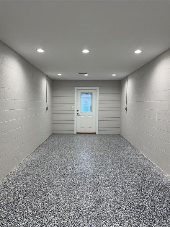 A garage interior with painted block walls, horizontal siding, recessed lighting, and a speckled floor — 110 SPIRIT LAKE ROAD UNIT 8, WINTER HAVEN, FL