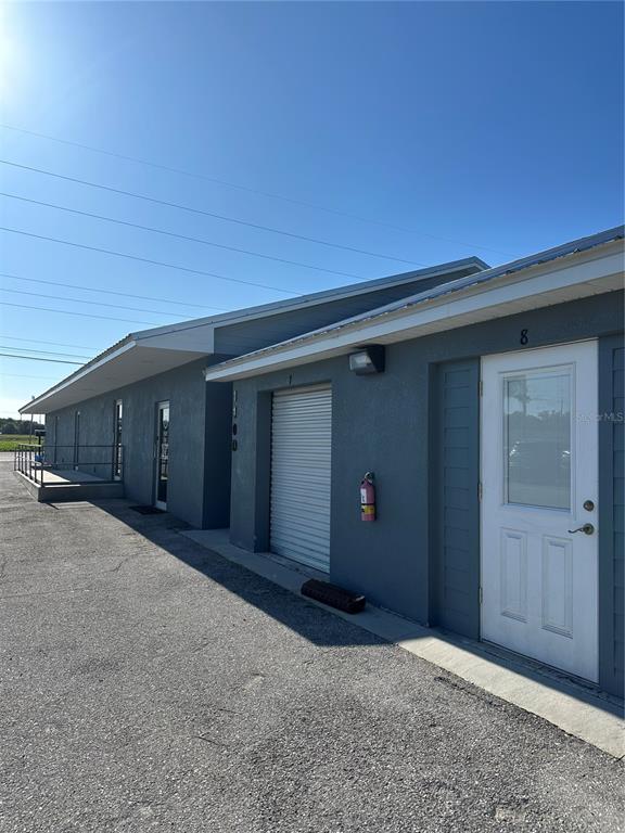 An exterior view of a gray commercial building featuring multiple unit doors and a roll-up door — 110 SPIRIT LAKE ROAD UNIT 8, WINTER HAVEN, FL