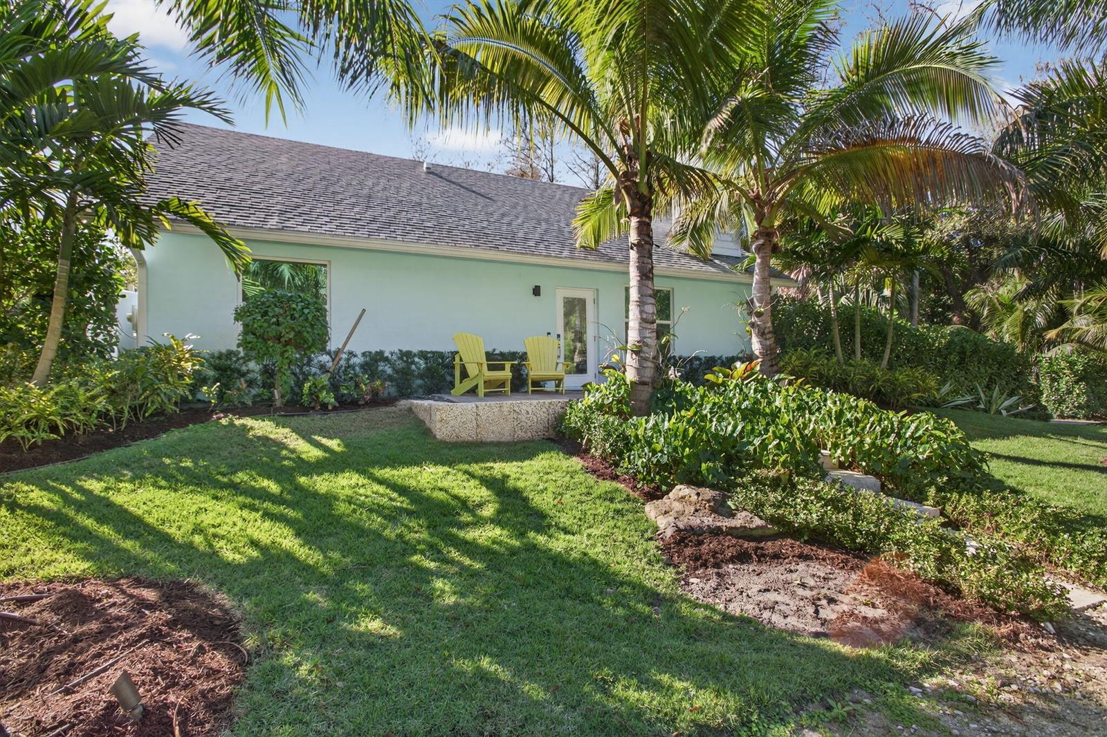 A light blue house with a stone patio and two yellow chairs in a garden — 9576 171st Street N, Jupiter FL 33478, JUPITER, FL
