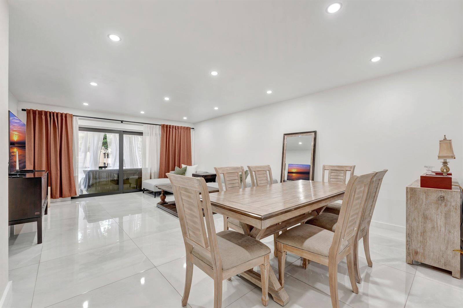A dining area with a wooden table and chairs sits on white tiled floors — 138 S Cypress Road # 224, Pompano Beach FL 33060, POMPANO BEACH, FL