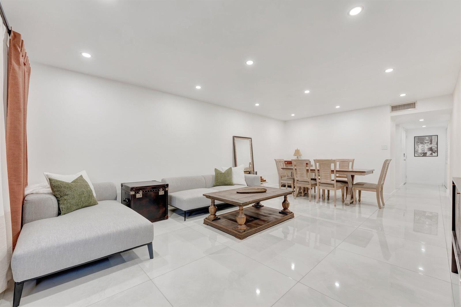 A bright, open-concept living and dining area features white tile floors and neutral furniture — 138 S Cypress Road # 224, Pompano Beach FL 33060, POMPANO BEACH, FL