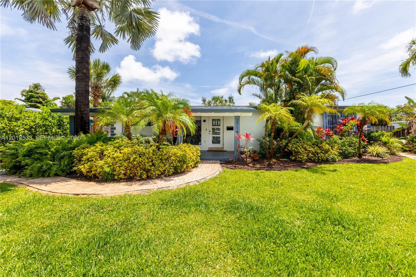 A single-story house with a white exterior, a brick walkway, and lush tropical landscaping — 2716 NW 3rd Ave, Wilton Manors FL 33311, WILTON MANORS, FL