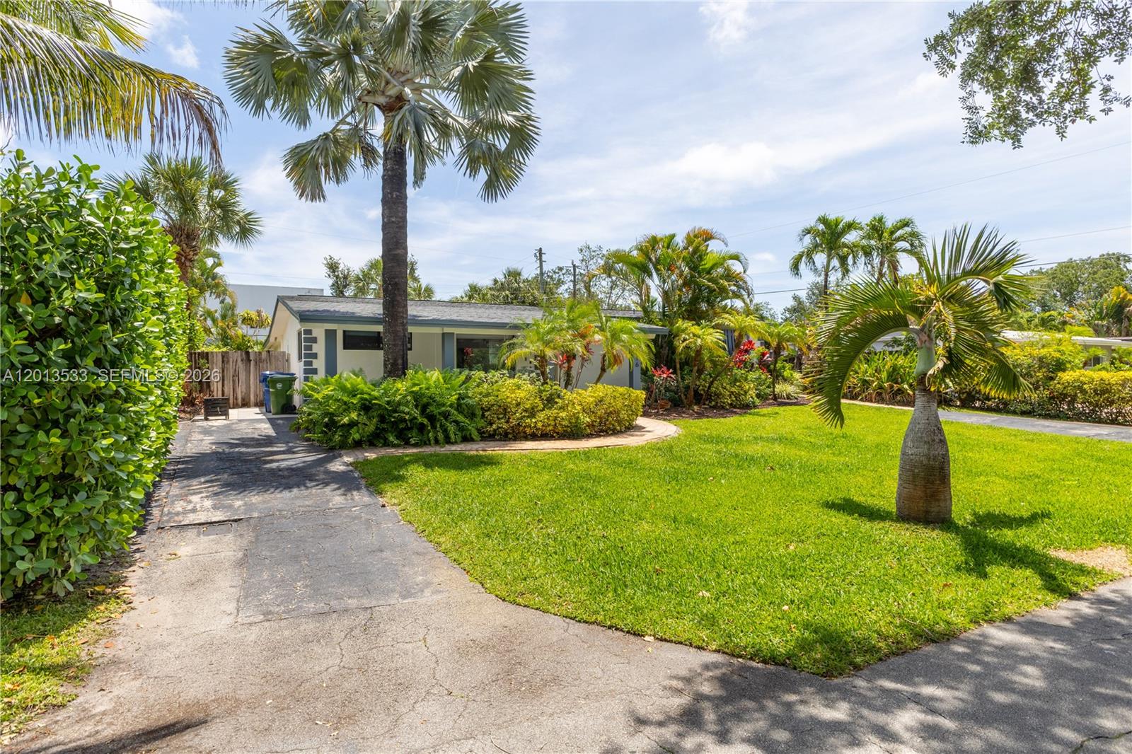 A single-story house with a driveway and palm trees sits behind a green lawn — 2716 NW 3rd Ave, Wilton Manors FL 33311, WILTON MANORS, FL