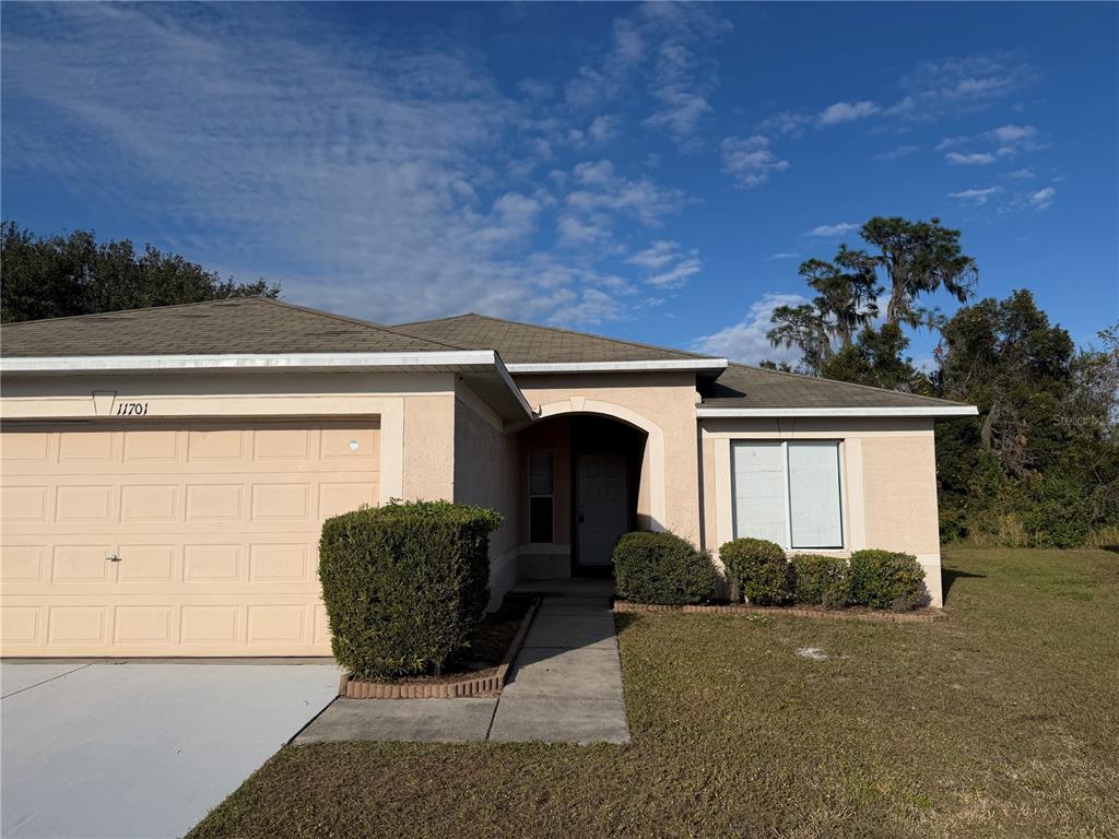 A single-story house with a beige stucco exterior, a two-car garage, and a front walkway — 11701 BRENFORD CREST DRIVE, RIVERVIEW, FL