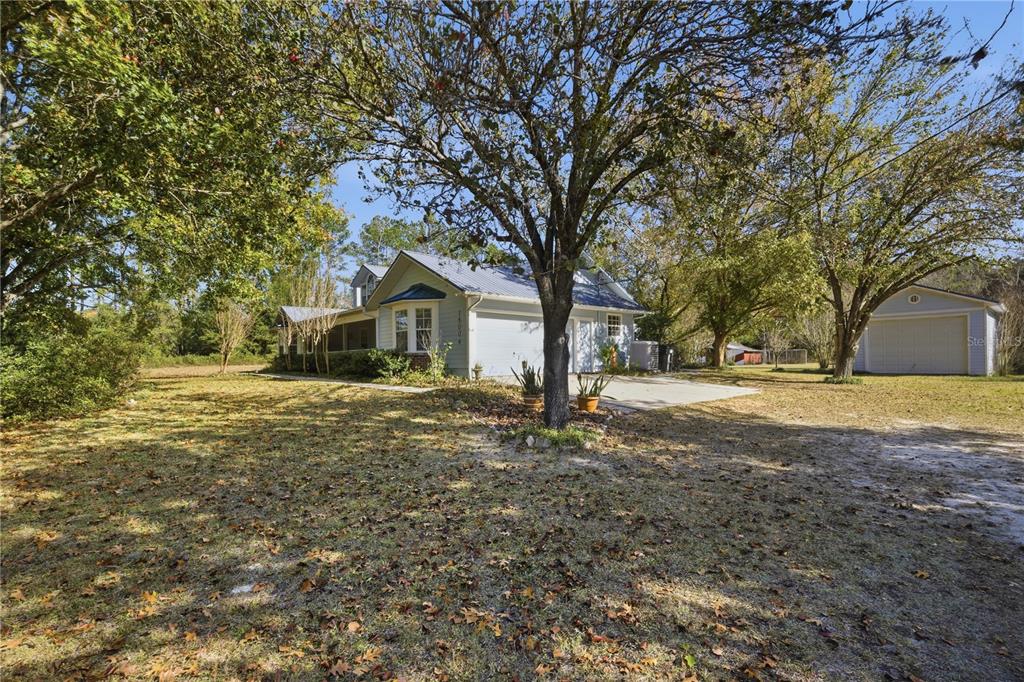 A light blue house with a metal roof and a detached garage sits on a lawn — 18004 NW 55TH PLACE, ALACHUA, FL