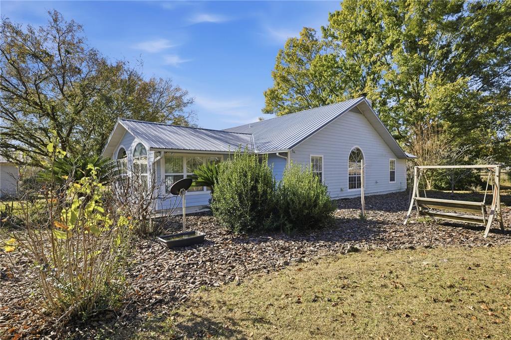 A light blue house with a metal roof and a wooden swing in the yard — 18004 NW 55TH PLACE, ALACHUA, FL