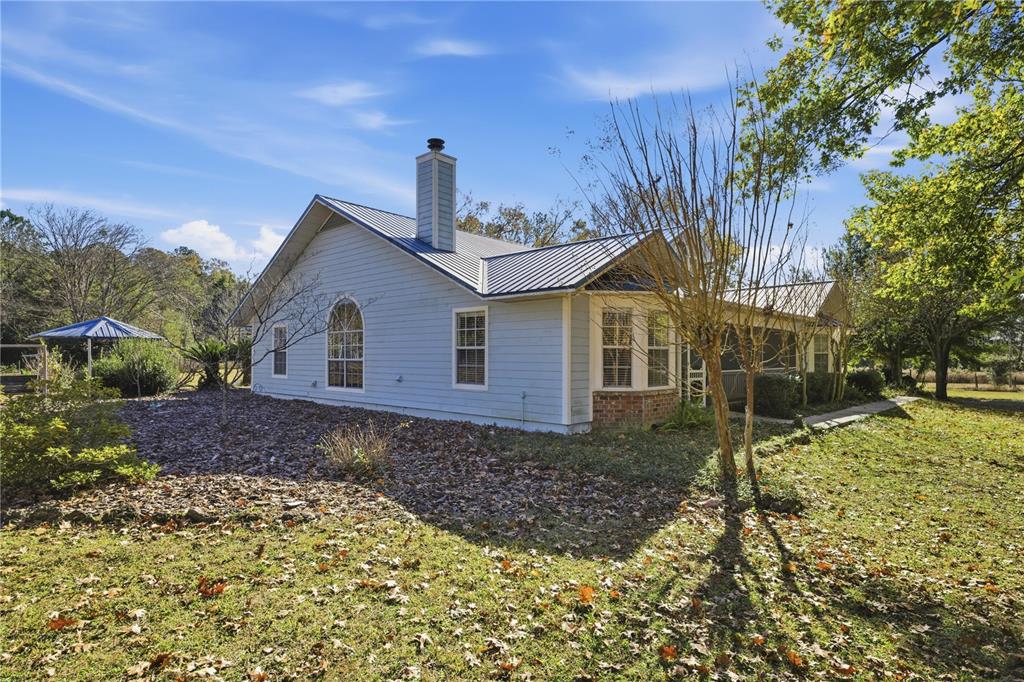 A light blue house with a metal roof and a brick-accented bay window — 18004 NW 55TH PLACE, ALACHUA, FL