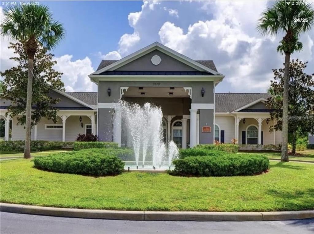 A fountain sits in front of a gray and beige building with a covered entrance — 3175 FELTRIM PLACE UNIT 203, KISSIMMEE, FL