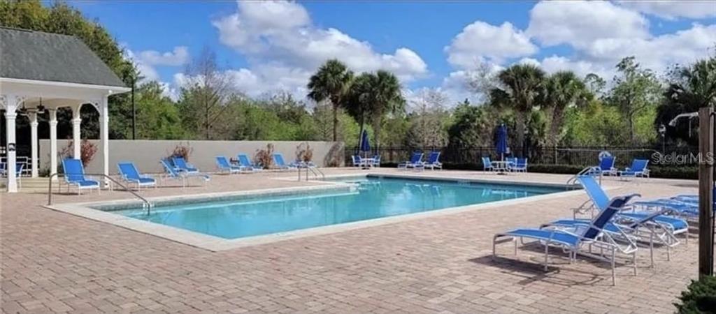 A rectangular swimming pool is surrounded by a brick patio with lounge chairs and a gazebo — 3175 FELTRIM PLACE UNIT 203, KISSIMMEE, FL