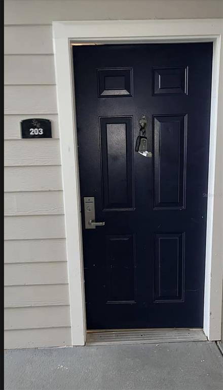A dark blue front door with a key hanging from the handle at unit 203 — 3175 FELTRIM PLACE UNIT 203, KISSIMMEE, FL
