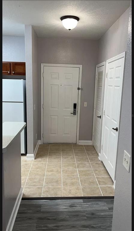 An entryway with tiled flooring, a white front door, and two adjacent white interior doors — 3175 FELTRIM PLACE UNIT 203, KISSIMMEE, FL