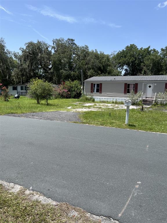 A single-story manufactured home sits on a grassy lot with a paved road in front — 4901 LILLIAN BLACK ROAD, ST CLOUD, FL