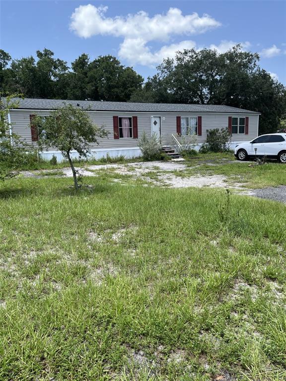 A single-story manufactured home with light siding and red shutters sits on a grassy lot — 4901 LILLIAN BLACK ROAD, ST CLOUD, FL