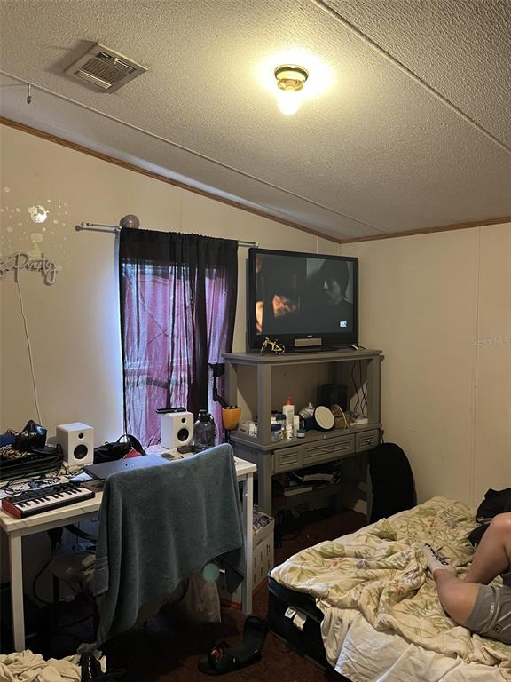 A bedroom features a desk with music equipment, a television on a stand, and a bed — 4901 LILLIAN BLACK ROAD, ST CLOUD, FL