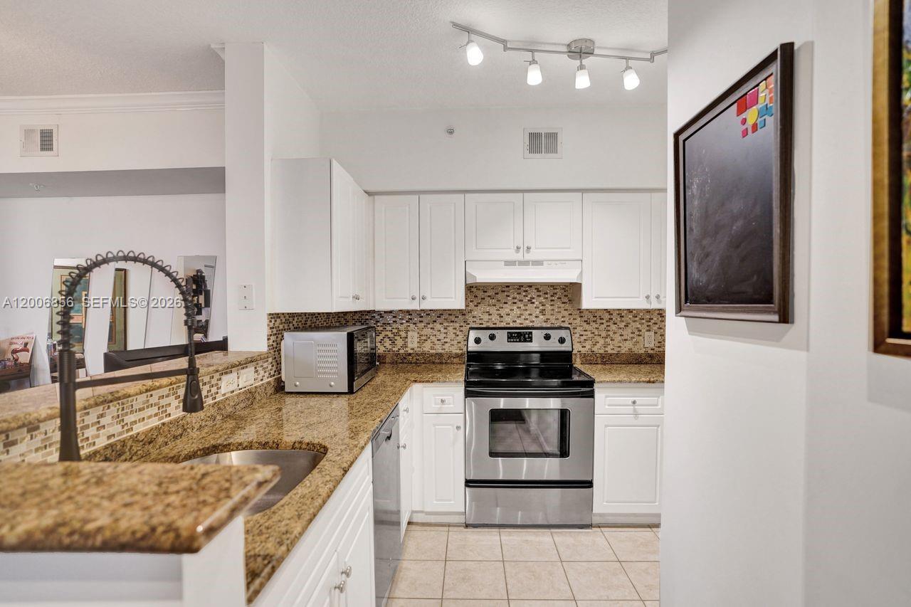 A kitchen features white cabinets, granite countertops, stainless steel appliances, and a tile backsplash — 2220 Tuscany Way # 2220, Boynton Beach FL 33435, BOYNTON BEACH, FL