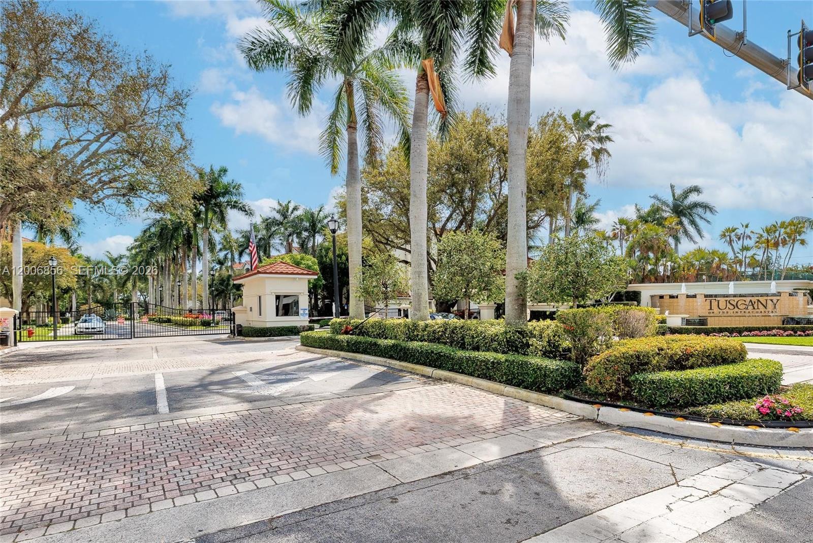 The entrance to a gated community features a guardhouse, palm trees, and a stone sign — 2220 Tuscany Way # 2220, Boynton Beach FL 33435, BOYNTON BEACH, FL