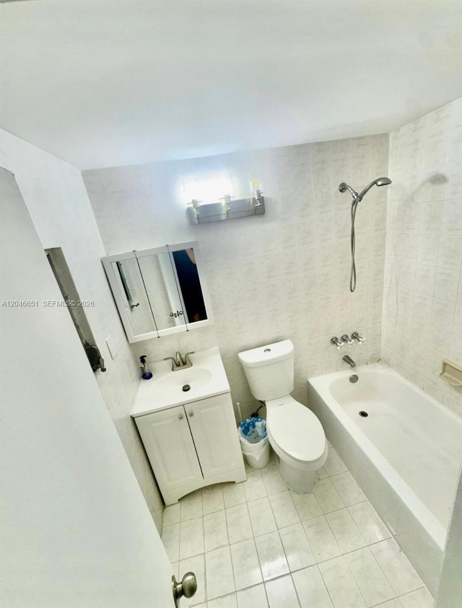 A small bathroom features a white vanity, a toilet, and a bathtub with a shower — 1922 NW 4th St # B, Miami FL 33125, MIAMI, FL