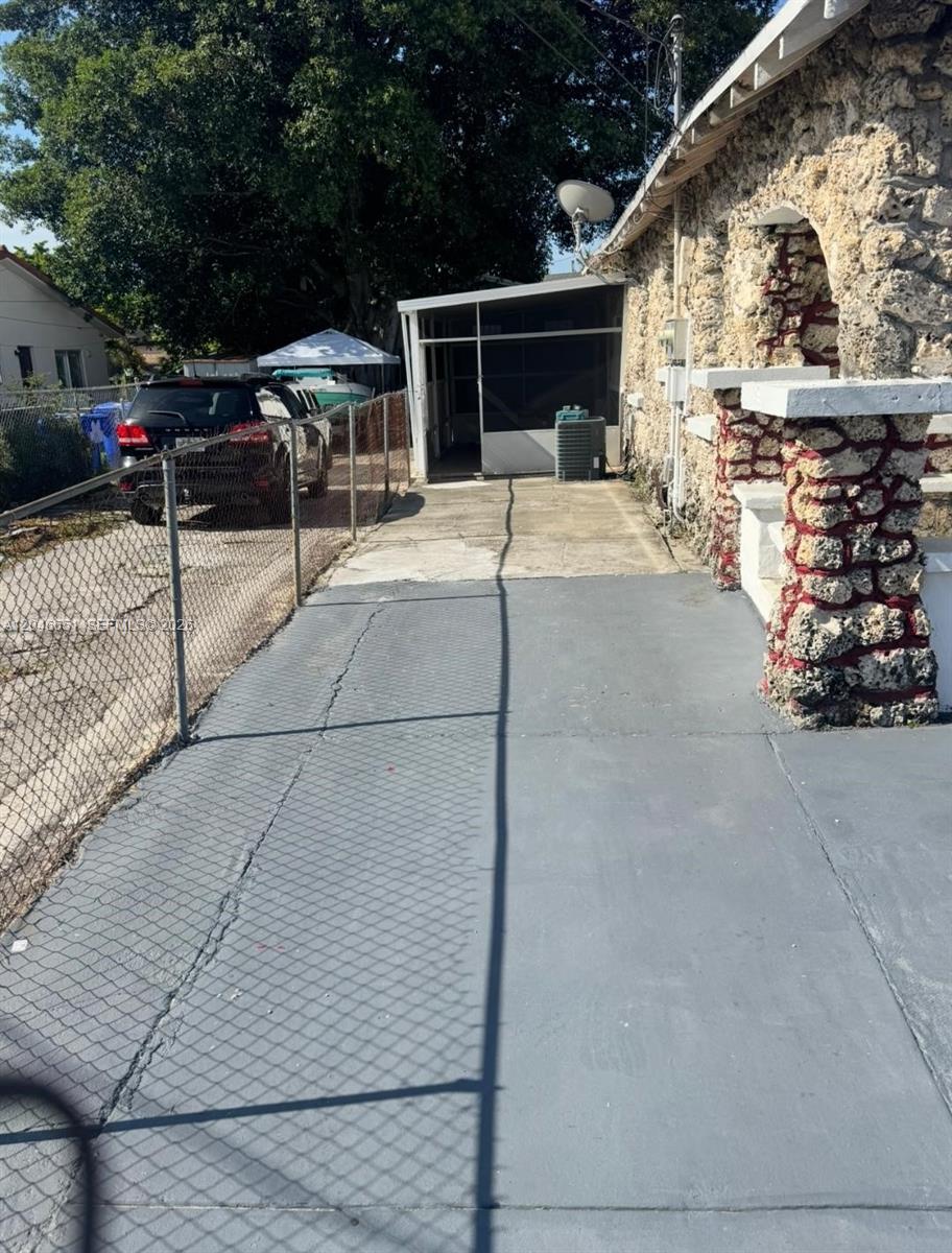 A stone-faced house exterior features a gray concrete driveway and a screened-in porch area — 1922 NW 4th St # B, Miami FL 33125, MIAMI, FL