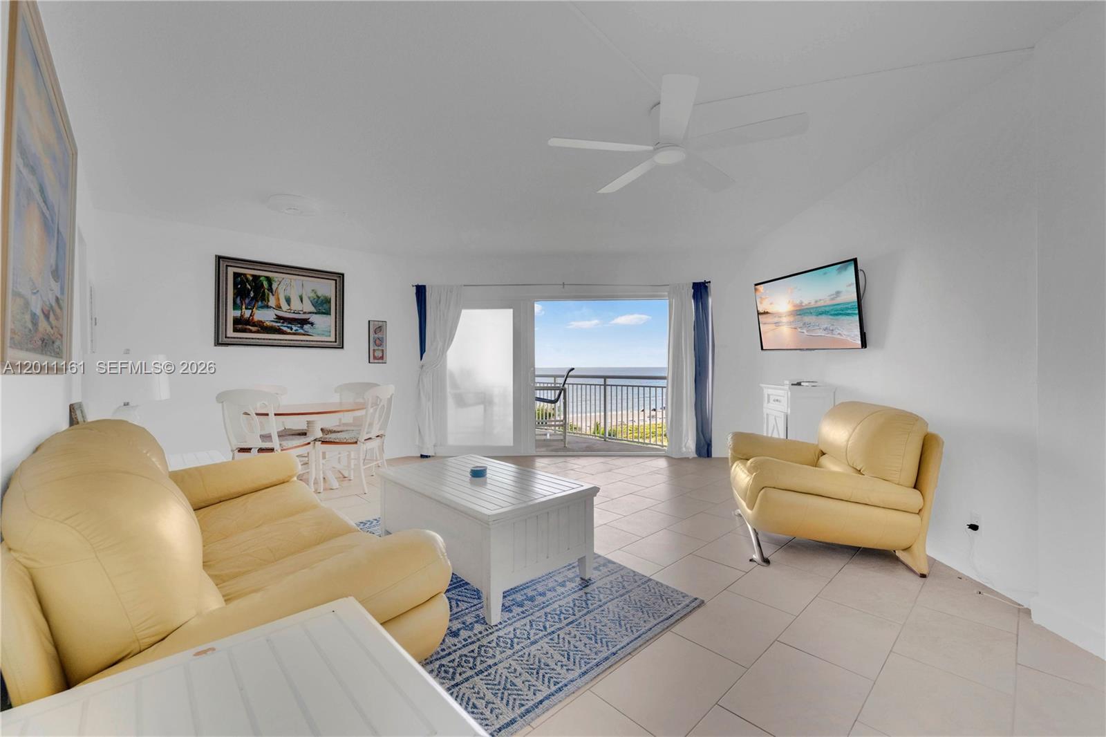 A living room features yellow leather furniture, a white coffee table, and a balcony view — 710 N Ocean Blvd # 511, Pompano Beach FL 33062, POMPANO BEACH, FL