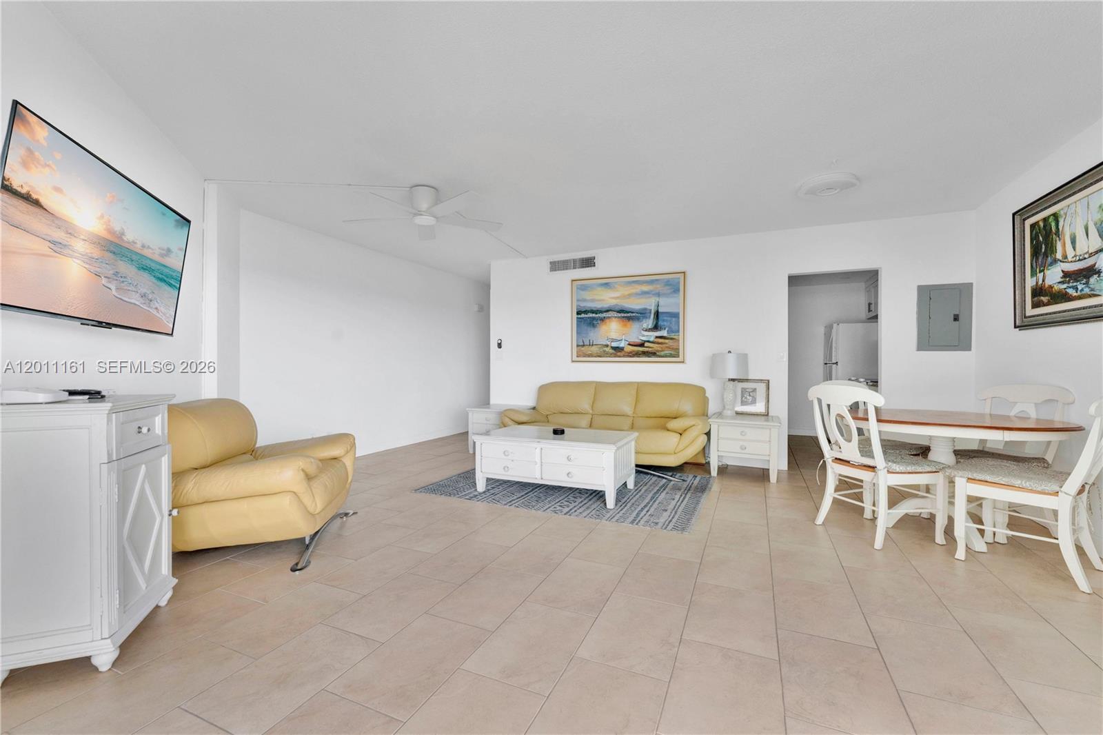 This living and dining area features tile flooring, white furniture, and a yellow sofa — 710 N Ocean Blvd # 511, Pompano Beach FL 33062, POMPANO BEACH, FL