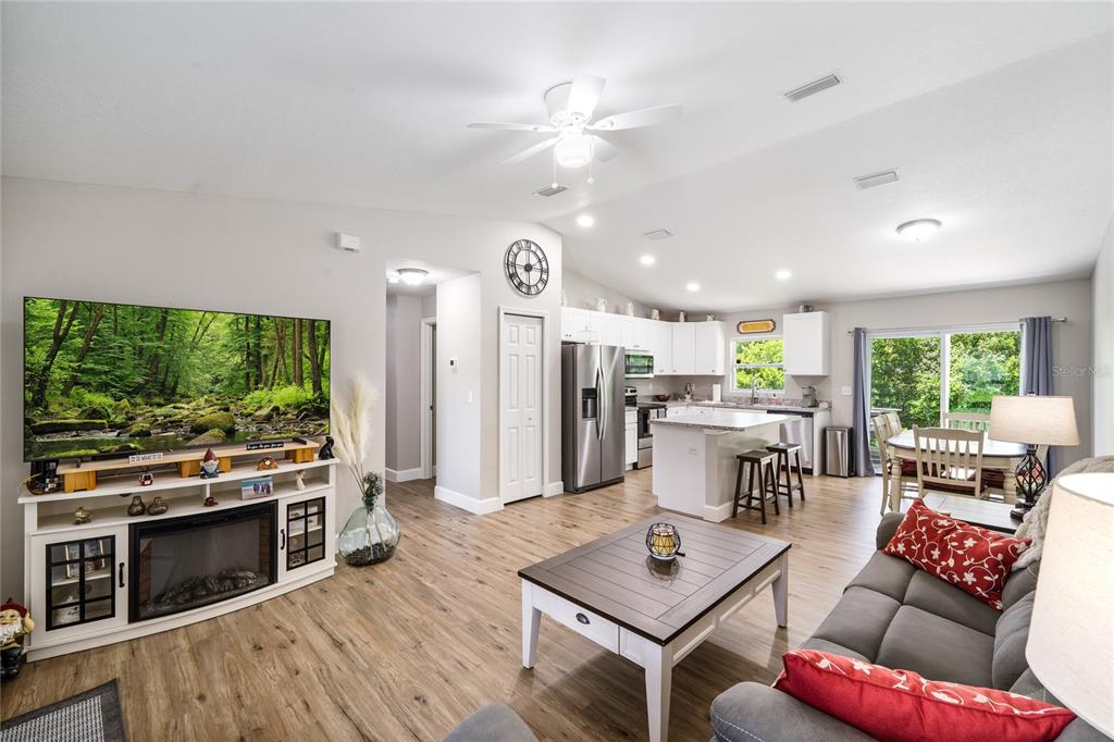 An open-concept living room and kitchen featuring wood-look flooring, a fireplace, and stainless appliances — 351 W ELM DRIVE, ORANGE CITY, FL