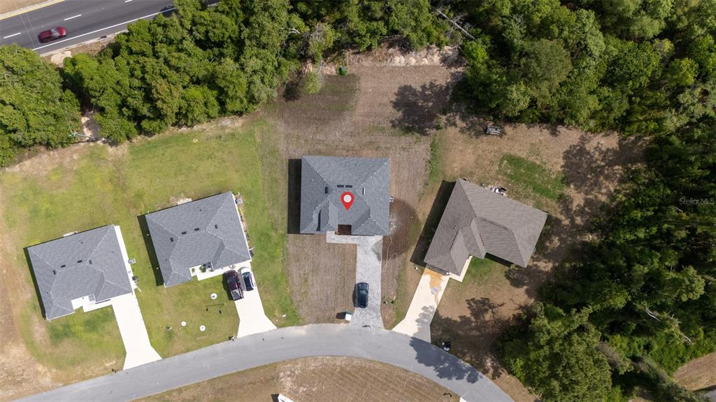 An aerial view shows three houses with driveways situated along a curved road near woods — 13621 SW 40TH CIRCLE, OCALA, FL